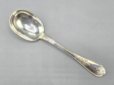 an antique silver spoon on a gray surface with a silver handle