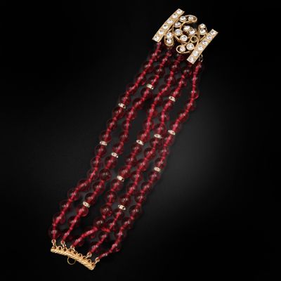un gros plan sur un bracelet en perles rouges muni d'un fermoir doré