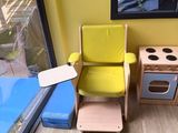 a yellow chair sitting in front of a window next to a stove