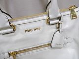 a white purse with a gold handle on a table