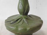 a green vase with a flower on it sitting on a table