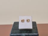 a close up of a pair of gold earrings on a marble block