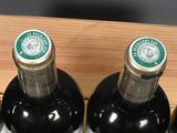 four bottles of wine in a wooden holder on a table