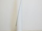 a tall white vase with a green handle on the floor