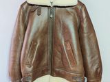 une veste en cuir marron suspendue à un cintre accroché au mur