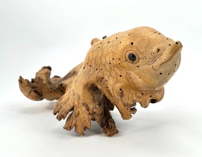 a wooden sculpture of a fish on a white surface