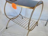 a metal table with a glass top and a magazine rack