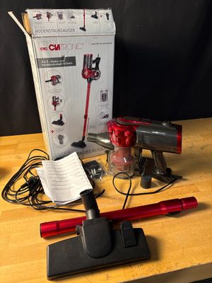 un aspirateur rouge à fil posé sur une table en bois, à côté d'une boîte