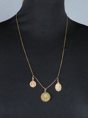 a woman wearing a gold necklace with three medallions on it