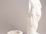 a statue of a woman standing next to a candle holder