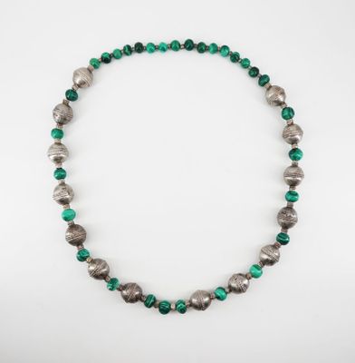 a close up of a necklace with green and silver beads