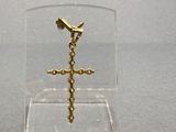 une petite croix en or dans un présentoir transparent