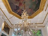un lustre au milieu d'une pièce dont le plafond est orné d'une peinture