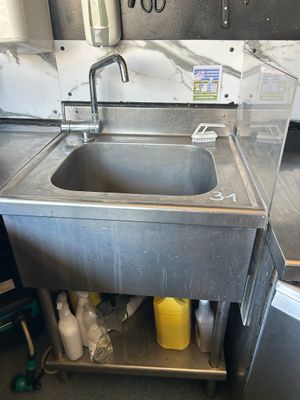 un évier au milieu d'une cuisine dont le plan de travail est encombré