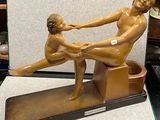 une statue représentant un homme et une femme assis sur un banc