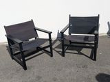 two black chairs sitting next to each other in a parking lot