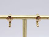 a close up of a pair of earrings on a gold stand
