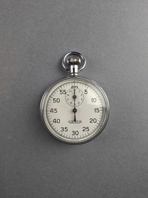 a close up of a silver stopwatch on a gray surface