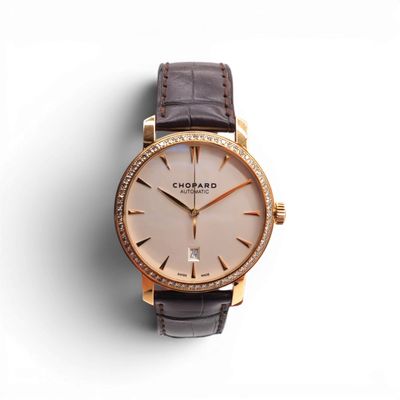 a close up of a watch on a white surface with a brown strap