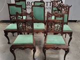 six antique chairs with green cushions and carved backrests
