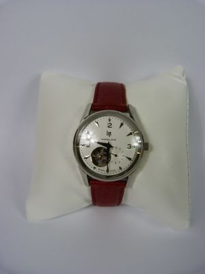 une montre blanche avec un bracelet rouge posée sur un coussin blanc