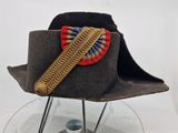 un chapeau marron orné d'un ruban rouge, blanc et bleu