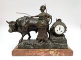 a bronze statue of a woman on a oxen with a clock