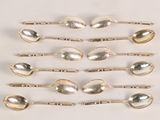 six silver spoons are lined up in a row on a white surface