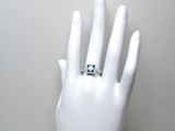 une bague sur la main d'un mannequin, sertie d'une pierre verte