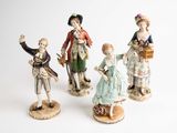 three figurines of people dressed in different styles of clothing