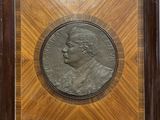 a bronze medallion of a man in a wooden frame