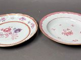 two plates with floral designs on them sitting on a table