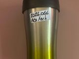 une tasse à café sur laquelle est collé un autocollant, posée sur une table
