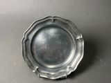 an antique silver plate on a table with a black background
