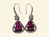 a pair of earrings with pink stones and diamonds on them