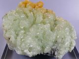 a small piece of green and yellow mineral on a clear plate