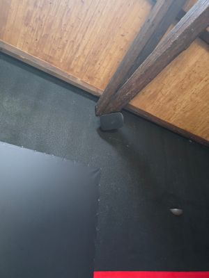a picture of a bathroom with a black floor and a wooden ceiling