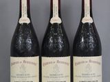 trois bouteilles de vin sont posées sur une étagère en verre devant un mur gris