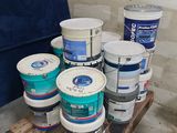 several buckets of paint sitting on top of a pallet in a room