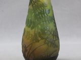 a green and black vase sitting on a white surface