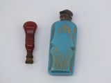 a small blue bottle and a red object on a white surface