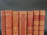 six red books lined up in rows on a black surface