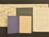 an old book with a purple cover sitting on top of a table next to a map