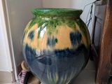 a green and blue vase sitting on the floor next to a wall