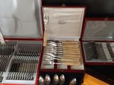 silverware in a red case sitting on top of a table next to other silverware
