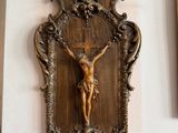 un crucifix en bois accroché au mur d'une pièce où se trouvent des photos encadrées
