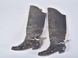 pair of black cowboy boots with chains on them on a white surface