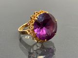 une image représentant une bague en pierre violette posée sur une surface noire