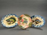 three plates with fish painted on them sitting next to each other