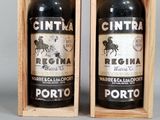 two bottles of wine in a wooden box on a gray surface
